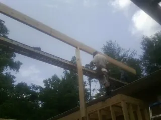 Carpenter setting a ridge beam over a new addition frame — Ice Dam Removal by Roofing Brothers in Center Harbor