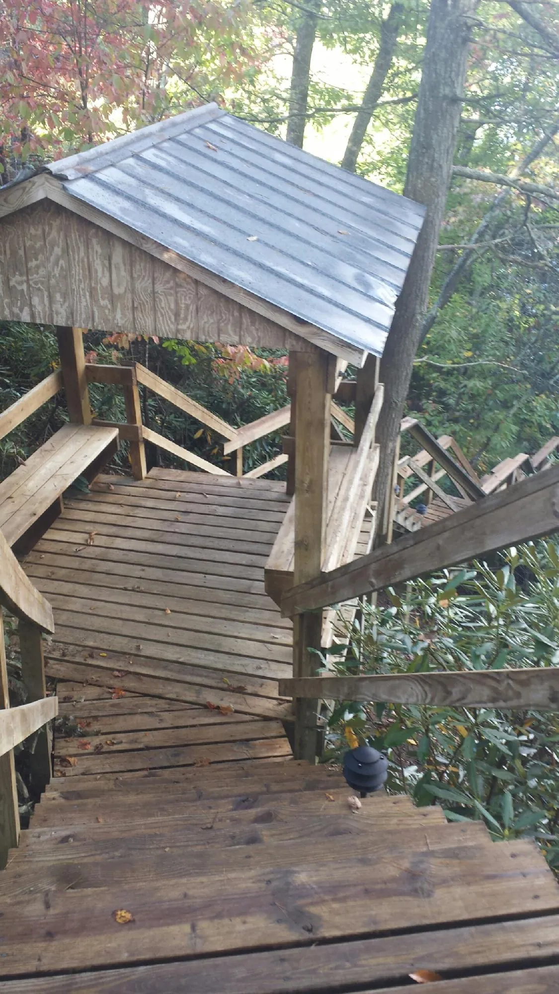 Metal roofed shelter over wooden steps on a wooded walkway — Skylight Repair & Installation work by our crew in Center Harbor