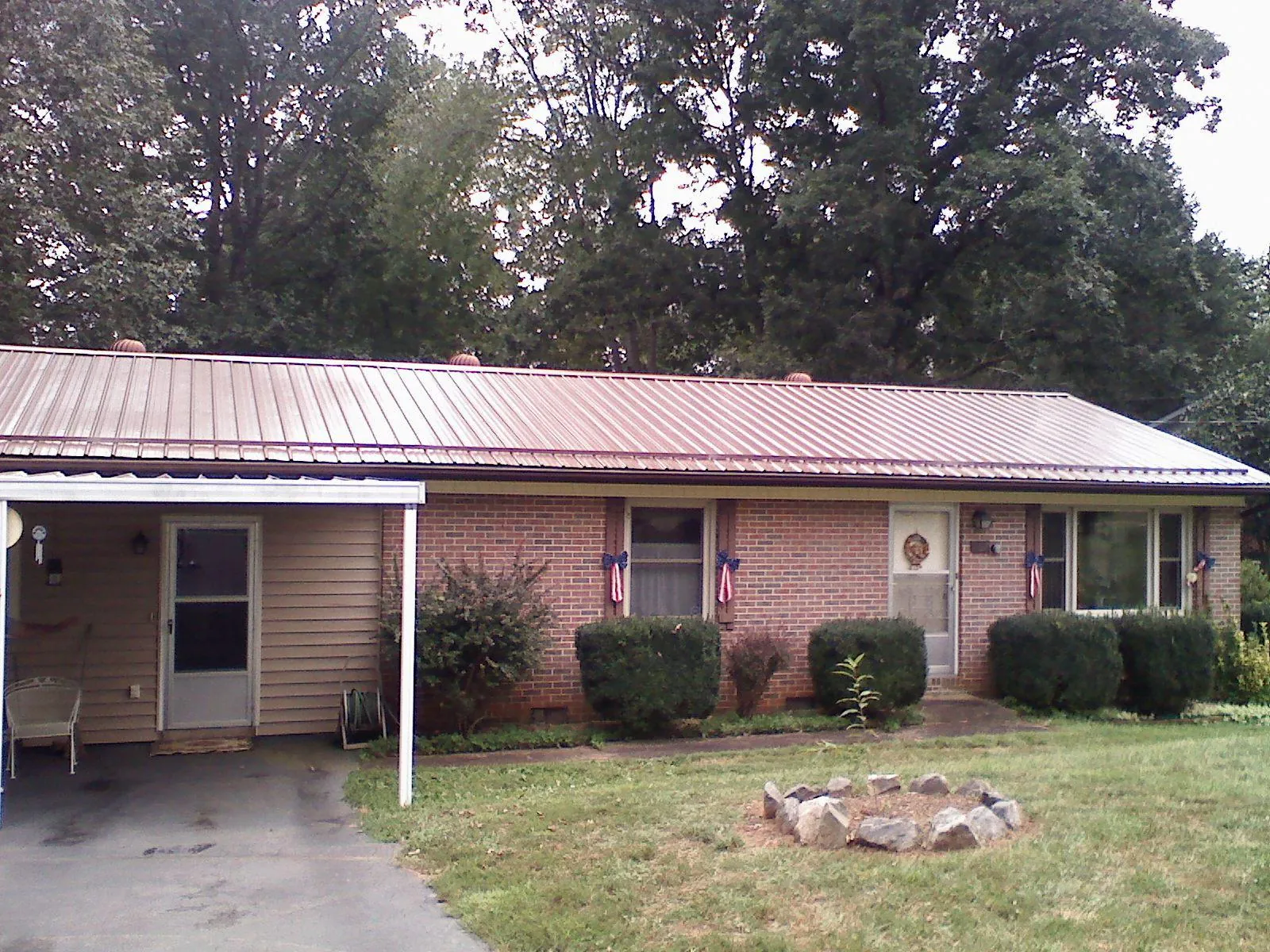 Bronze metal roof and carport on a brick ranch home — Roof Repair work by our crew in Center Harbor